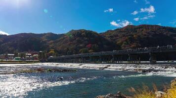 A timelapse of cloud and tourists near Togetsukyo bridge in Kyoto wide shot tilt video