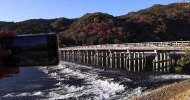 A smartphone shooting Togetsukyo bridge near Katsuragawa river in Kyoto in autumn video