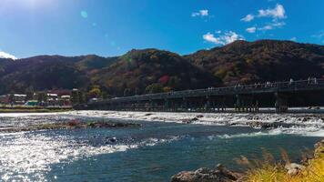 un lapso de tiempo de nube y turistas cerca togetsukyo puente en Kioto amplio Disparo video