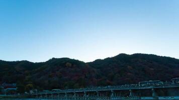 A dusk timelapse of Togetsukyo bridge in Kyoto in autumn wide shot panning video