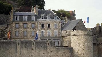 incroyable vieux brique maison sur le Roche entouré par haute brique mur et une la tour avec touristes, architecture concept. action. ancien pierreux bâtiment avec le drapeaux de France, européen syndicat et la Normandie. video