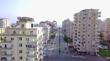 oben Aussicht von Stadt Straße führen zu Meer. Clip. Straße Vorbeigehen unter Hochhaus Gebäude von Stadt führt zu Meer auf Horizont. oben Aussicht von Gerade Straße unter Hotels von Resort Stadt, Dorf durch Meer video