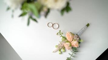 Wedding boutonniere and wedding rings on brown cloth. Wedding rings and boutonniere photo