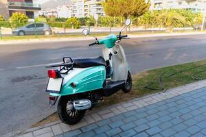 Blue moped scooter parked on the sidewalk photo