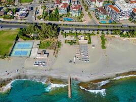 Drone shot of city, football field and seashore with blue sea and beach photo