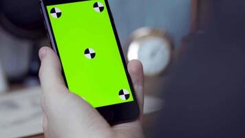 uomo utilizzando mobile smartphone a casa. azione filmato. vicino su di un' Telefono con un' verde schermo nel il mani di un' uomo video