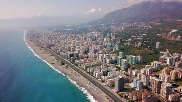 parte superior ver de hermosa grande ciudad por mar en antecedentes de montañas. acortar. panorama de del Sur recurso pueblo situado en costa de azul mar y montaña paisaje video