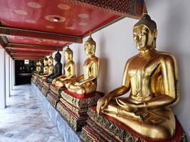 Golden Buddha Images at the hall way at Wat Pho Temple where is a Famous Temple and Historical Landmark of Bangkok Thailand, that Located beside Temple of the Emerald Buddha. photo