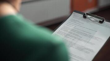 mujer con carpeta tableta y texto ver desde detrás. negocio mujer con bolígrafo y papel carpeta. joven bonito trabajador escritura alguna cosa en su documentos ver desde atrás. un mujer es participación azul carpeta para video