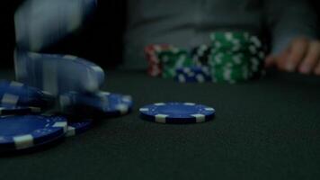 Throw the blue chips in poker. Blue and Red Playing Poker Chips in Reflective black Background. Closeup of poker chips in stacks on green felt card table surface in slow motion video