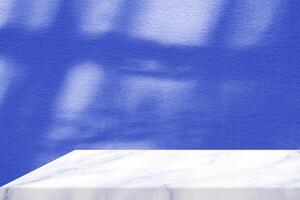 White Marble Table Corner with Light Beam, Shadow, and Spotlight on the Blue Concrete Wall Background, Suitable for Product Presentation Backdrop, Display, and Mock up. photo