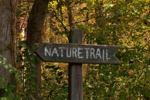 This trail marker has been paced at the beginning of the path. It is put here to make the entrance so hikers could find their way. The brown signage posted with white letters stating the title. photo