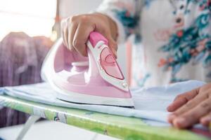 Close up of woman ironing clothes on ironing board photo