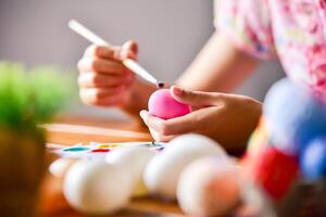 young girl painting Easter eggs for eastertime at home photo