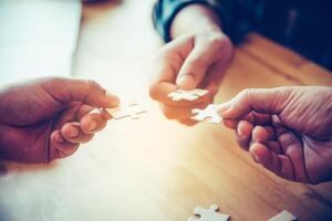 Business team handle a piece of white puzzles that are about to drop to get a complete worksheet - An attempt to succeed. photo