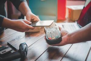 Customer paying bill through smartphone using NFC technology.Closeup of hand making payment through contactless machine. photo