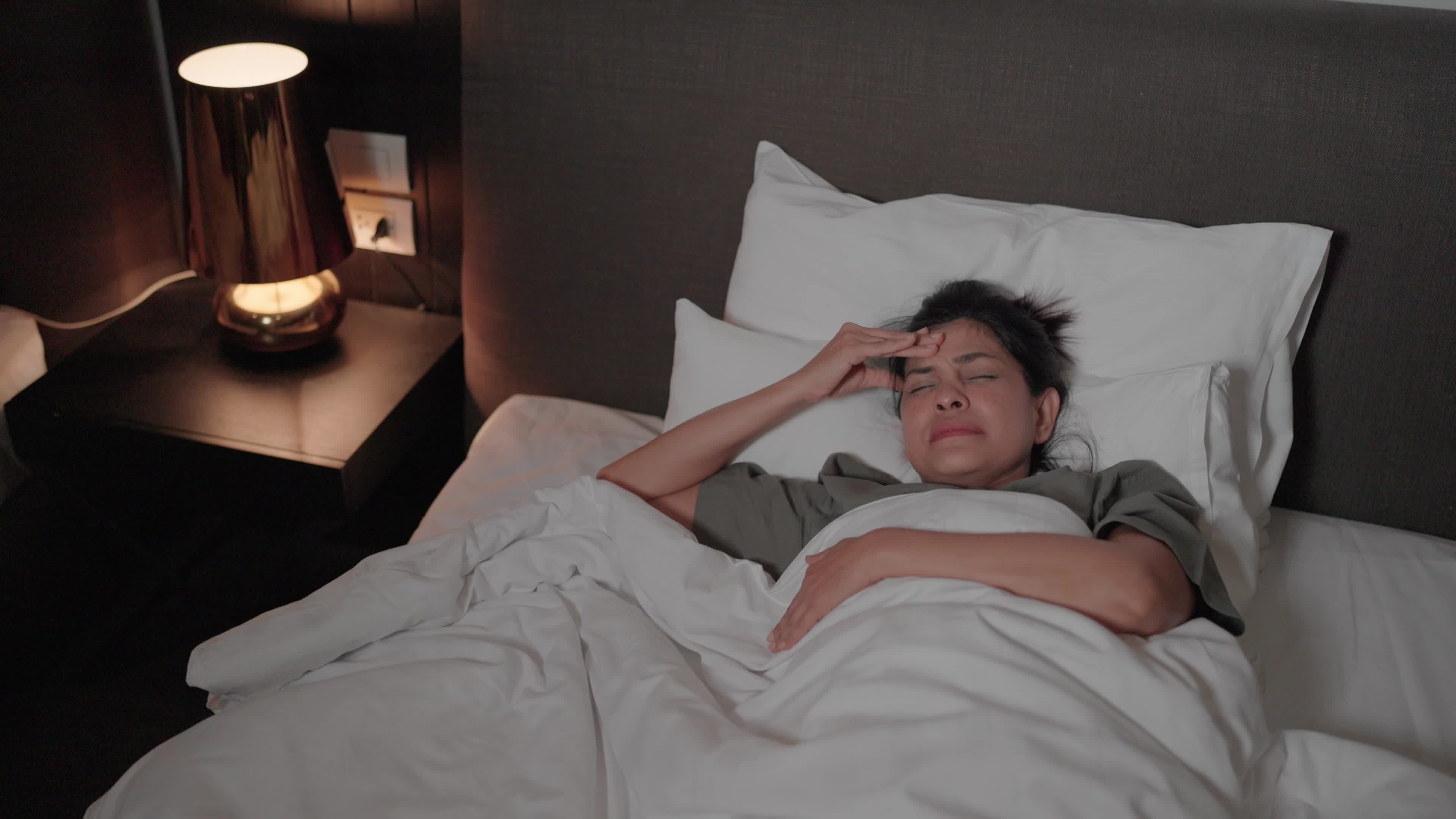 Close up of a young woman having trouble sleeping moving around in bed