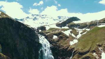 antenn alpina berg, vattenfall, snö keps. montera regnigare och alpina ängar från de horisont spår. antenn se av myrten falls berg vildmark video