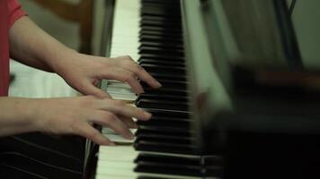 meisjes handen Aan de toetsenbord van de piano. de meisje Toneelstukken piano, dichtbij omhoog piano. handen Aan de wit sleutels van de piano spelen een melodie. vrouwen handen Aan de toetsenbord, spelen de aantekeningen melodie. video