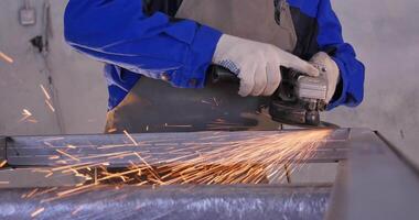 artigiano segare metallo con disco macinino nel officina. macinazione metallo con scintille volare. elettrico ruota macinazione su acciaio struttura nel fabbrica Basso velocità otturatore . metallo macinazione con arancia volante video