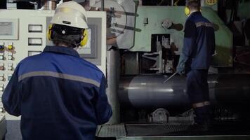 twee arbeiders in productie fabriek net zo team bespreken, industrieel tafereel in achtergrond. twee arbeider in fabriek Aan de machine. arbeider met uit veiligheid uitrusting gevangen in de machine video