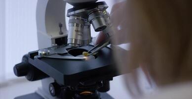 Serious clinician studying chemical element in laboratory. Close up of microscopic lens. Sample in microscope slide prepared for analysis in micro video