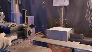 Craftsman sawing metal with disk grinder in workshop. Metal sawing close up. Worker in production sawing metal. Industry in slow motion video