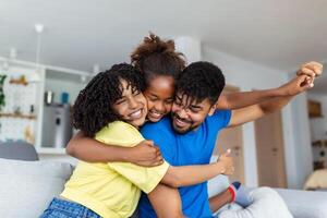 Happy African American dad and mom piggybacking excited proud daughter kid, playing flying superhero, reaching arm forward. Cheerful girl riding fathers back playing active game with family at home photo