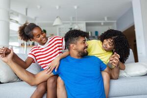 Loving diverse parents spend time with little adorable daughter have fun together at modern home smiling laughing, close up. Happy multi-ethnic family concept photo