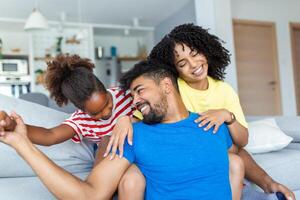 Positive cheerful multi-ethnic family wife husband child sitting together on couch at home. Close up focus on little daughter and beautiful mother. Happy multiracial family concep photo