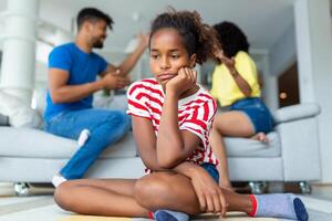 Child suffering from quarrels between parents in the family at home. Domestic violence and Family conflict concept. Sadness little girl against blured of mother fighting father with quarrel at home. photo