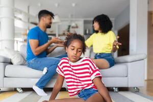Sad little girl is looking away while her parents are arguing in the background. Rising family problems hurt children's minds. Stop violence in children Help prevent abus photo