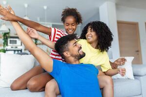 Family sitting on sofa smiling at camera on modern apartment background Happy family with daughter playing at home and weekend for family photo