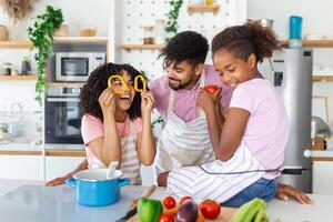 Happy African American parents and their kids having fun while cooking. photo