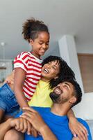 Happy dad and mom with their cute daughter hug and have fun sitting on the sofa in the living room at home. photo