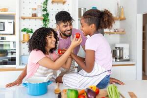 African American family with cute daughters preparing dietary meal natural nutrition, cutting fresh vegetable for salad, parents caring for children health eat organic food, weekend activity at home photo