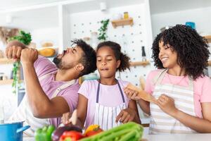 Kitchen Fun. Cheerful parents and their little daughter singing while cooking together. photo