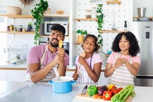 alegre joven padres y pequeño hija teniendo divertido mientras horneando juntos en cocina, contento africano americano familia canto y engañando, utilizando espátula y batidor como micrófonos, Copiar espacio foto