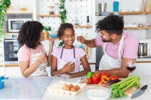 contento familia con su hija cocineros en cocina, amasa masa y hornea galletas foto