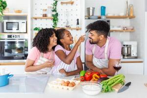 contento amoroso familia son preparando panadería juntos. madre, padre y niño hija niña son Cocinando galletas y teniendo divertido en el cocina. hecho en casa comida y pequeño ayudante. foto