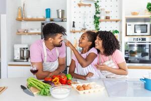 Overjoyed young family with Daughter have fun cooking baking pastry or pie at home together, happy smiling parents enjoy weekend play with child doing bakery cooking in kitchen photo