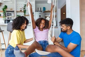 Mom and dad swinging and having fun with their daughter at home. photo