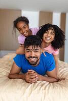 Happy family mother, father and daughter laughing, playing and jumping in bed in bedroom at home photo