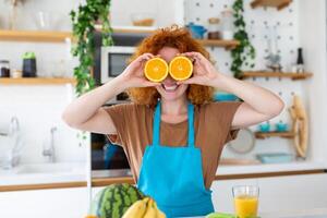 foto de linda caucásico mujer sonriente y participación dos naranja partes mientras Cocinando vegetal ensalada en cocina interior a hogar