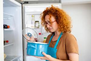 malo comida en refrigerador, joven mujer en participación su nariz porque de malo oler desde comida en refrigerador a hogar foto