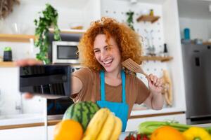 Young woman is in the kitchen, she has wireless headphones on, she is dancing and singing photo