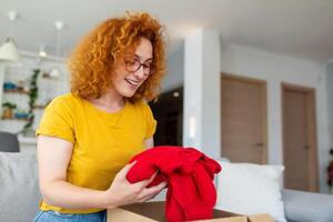 Young woman receiving parcel at home. Holiday shopping online and unpacking cardboard box. Delivery service during covid quarantine. Happy girl getting gift. Lifestyle moment photo