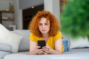 Woman using mobile phone while lying on sofa. Young female is resting at home. photo