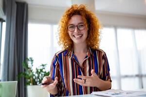 Shot of smiling business woman working with laptop while looking at camera in modern startup office. photo