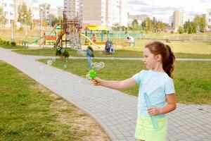 little girl blowing soap bubbles on the playground photo